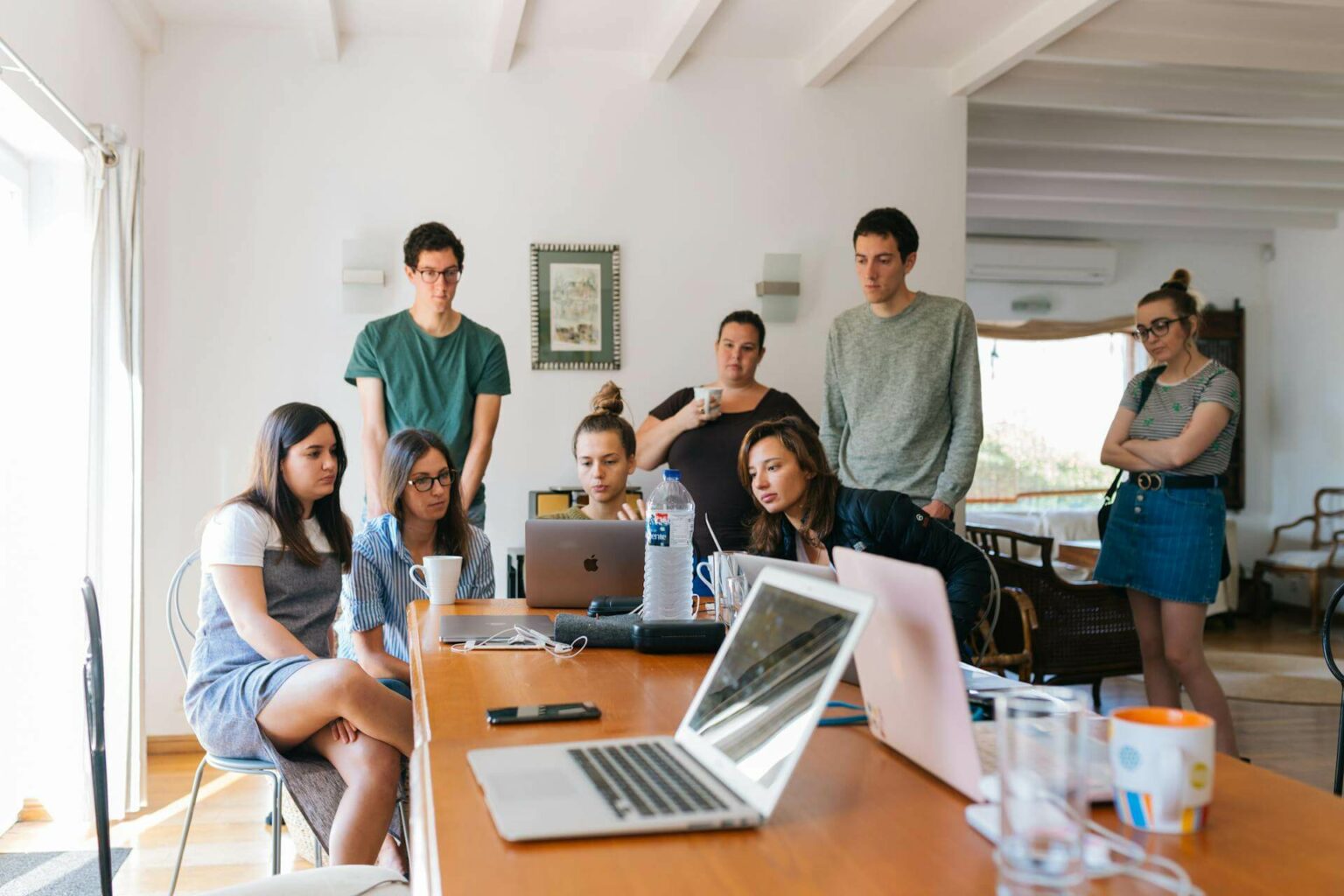 Beitragsbild zum Blogbeitrag über "Über uns Seite erstellen". Es zeigt ein Team aus Angestellten, die gemeinsam am Laptop eine Über-uns-Seite erstellen.