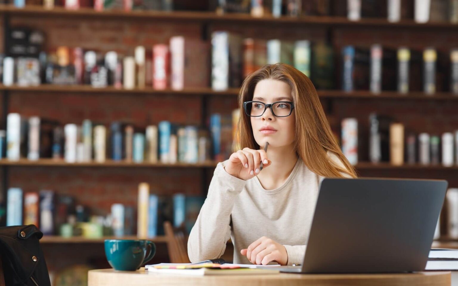 Junge Gründerin denkt am Laptop darüber nach, wie sie neue Kunden für B2B und B2C für ihr Unternehmen gewinnt.